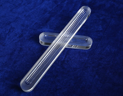 Dos piezas de vidrio de calibre reflejo con tres ranuras de diferente dimensión están en el suelo.