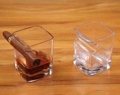Two cigar whisky glass cups are on the desk, one is equipped a cigar and the other is blank.