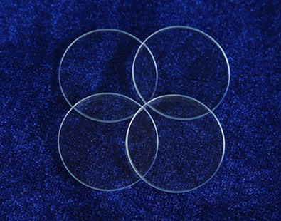 Four pieces of glass discs are on the ground and they are all bright, smooth and polished.
