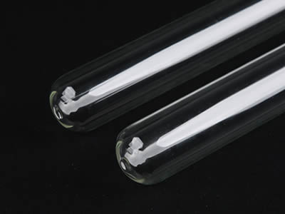 Dos tubos de ensayo de vidrio con fondo redondo sobre fondo negro.