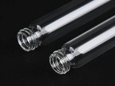 Dos tubos de ensayo de vidrio con tapa de tornillo sobre fondo negro.