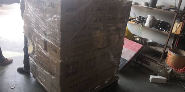 Several cartons are packed on the wooden pallet and wrapped with plastic film.