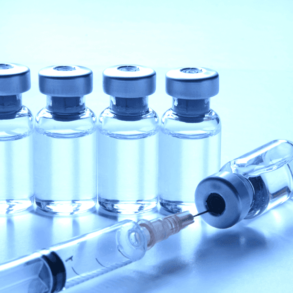 Six injection glass vials are placed with a syringe.